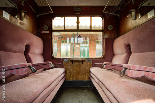 Colchester / Great Britain - May 12, 2013: Interior shot of vintage railway carriage showing seating and window.  Old station building can be seen through window.