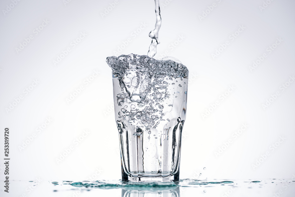water pouring in glass on white background with backlit, splashes and copy space water pouring in glass on white background with backlit, splashes and copy space