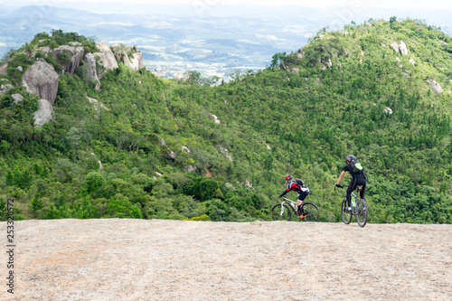 Two mountain bikers enjoy a ride on top of the Pedra Grande, a huge single piece mountain surrounded by the atlantic forest and by an amazing landscape in Atibaia, Sao Paulo, Brazil