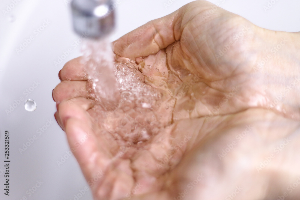 The water from the tap accumulated in the handful. On the white background. The water from the tap accumulated in the handful. On the white background.
