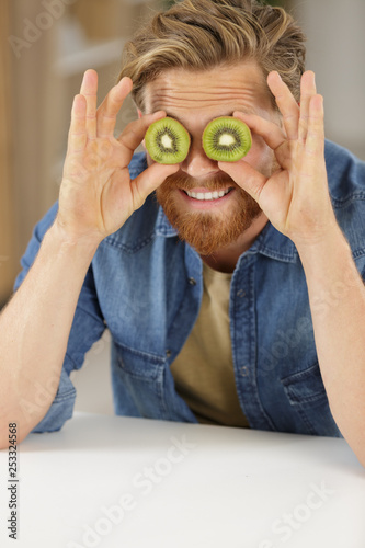 man covering his eyes with kiwi halves photo