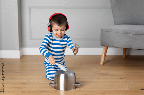Young child wearing headphones playing drums with pots and pans