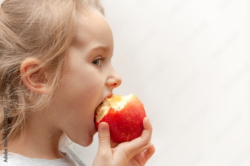 A little blonde girl eats a red apple A little blonde girl eats a red apple