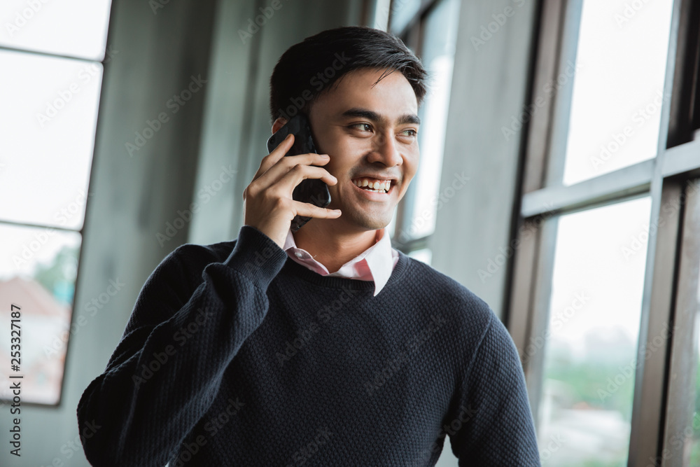 smiling businessman talking on his smartphone and looking at the window smiling businessman talking on his smartphone and looking at the window