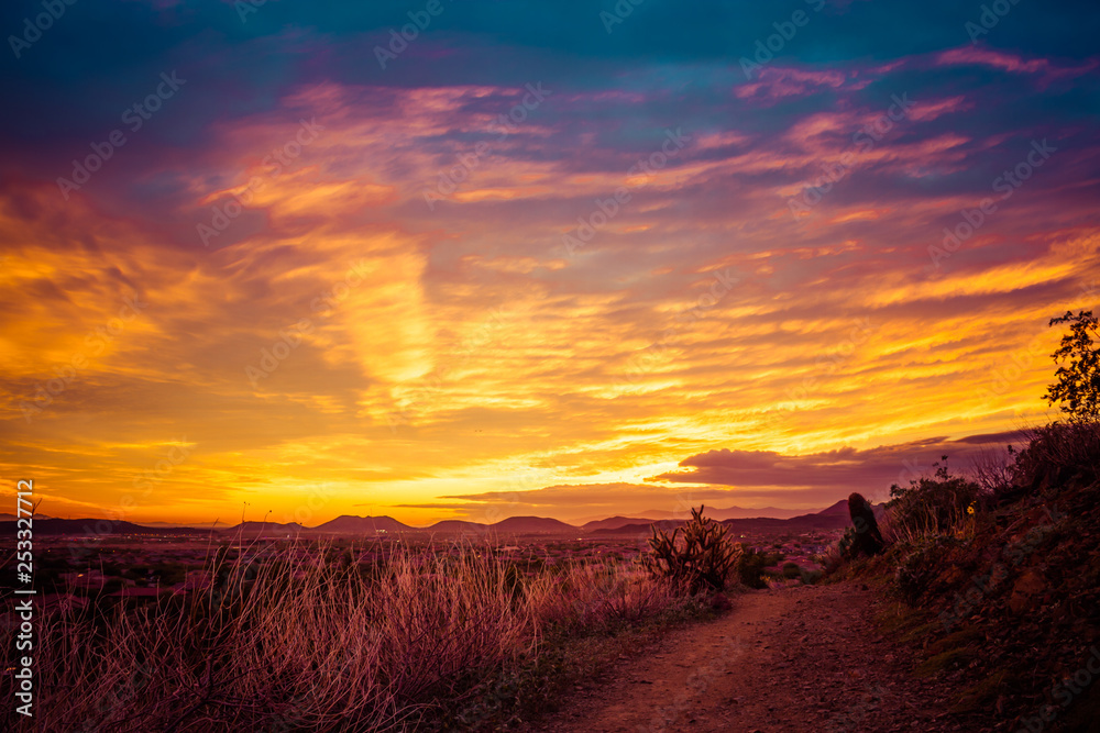 A trail through the desert of the American southwest in Arizona looking at a colorful sunset with clouds.