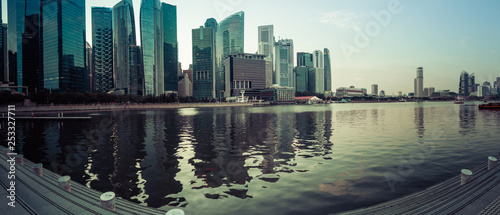 A panoramic image of downtown Singapore during the blue hour with the city lite up and reflecting in Marina bay below.