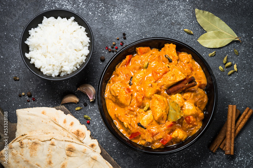Chicken tikka masala with rice on black top view.