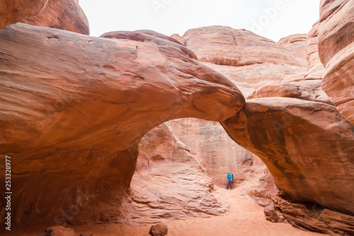 Young woman is looking at the Sand Dune Arch near Devils Garden Arches National Park Moab Utah. Travel and adventure concept. Hiking concept.