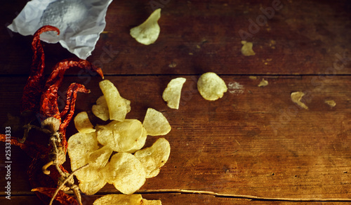 Potato chips with hot pepper and salt on rustic wood table