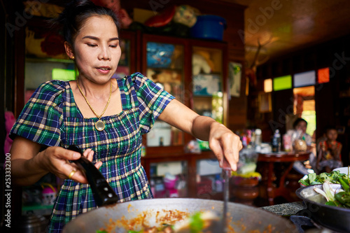 thai woman cooking traditional red curry in wok