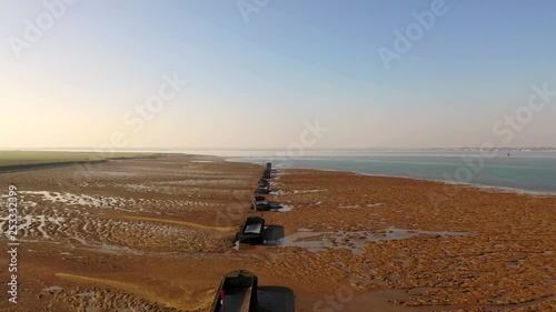 Aerial sequence featuring derelict WWII barges along the Essex coastline. Situated along the Blackwater River, part of the Dengie Peninsula and low-lying marshes near Bradwell in Essex.