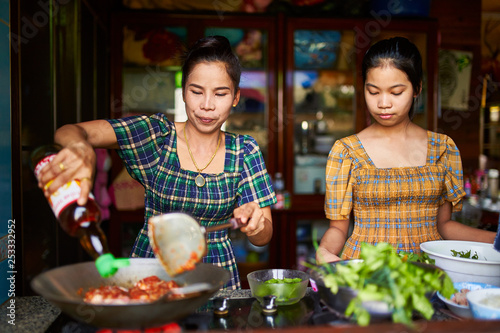 thai mother and daughter cooking red curry together in tradional home kitchen
