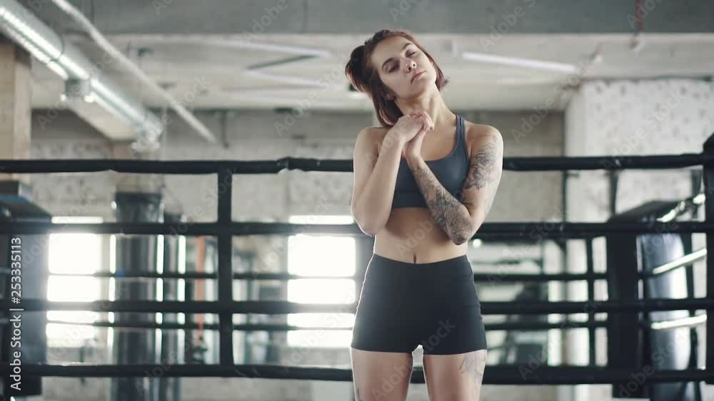 girl warms up on the background of the boxing ring. young woman doing stretching in the gym before exercise. girl warms up on the background of the boxing ring. young woman doing stretching in the gym before exercise.