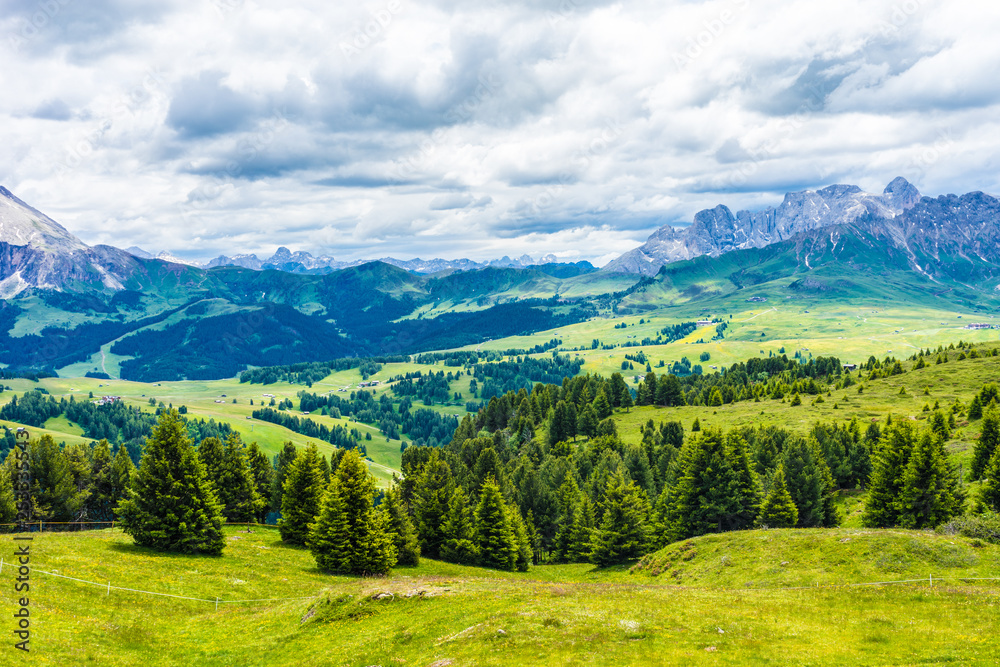 Alpe di Siusi, Seiser Alm with Sassolungo Langkofel Dolomite, a large green field with a mountain in the background Alpe di Siusi, Seiser Alm with Sassolungo Langkofel Dolomite, a large green field with a mountain in the background
