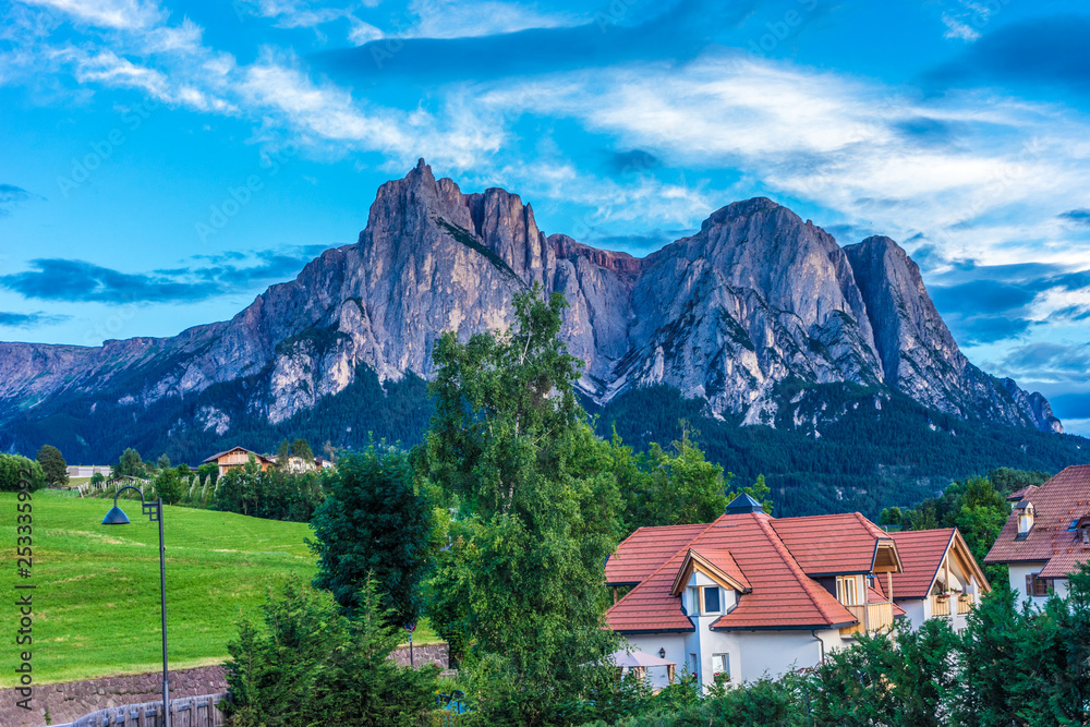 Alpe di Siusi, Seiser Alm with Sassolungo Langkofel Dolomite, a large green field with trees in the background Alpe di Siusi, Seiser Alm with Sassolungo Langkofel Dolomite, a large green field with trees in the background