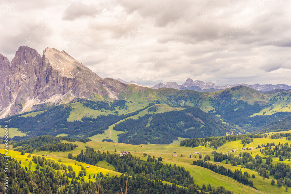 Fototapeta premium Alpe di Siusi, Seiser Alm with Sassolungo Langkofel Dolomite, a large green field with a mountain in the background
