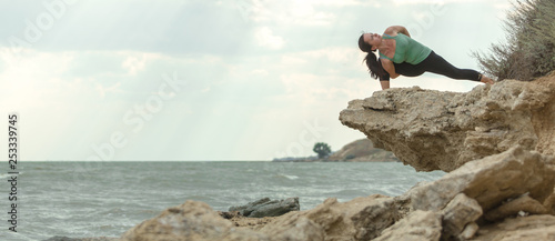 Young woman practicing yoga in nature. Ocean coast. Woman's happiness. Landscape background