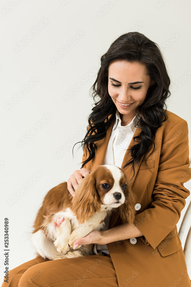 Attractive curly woman in brown jacket holding dog isolated on white Attractive curly woman in brown jacket holding dog isolated on white