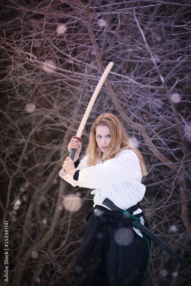 Obraz premium Female warrior. Woman with wooden sword practicing aikido in the snow