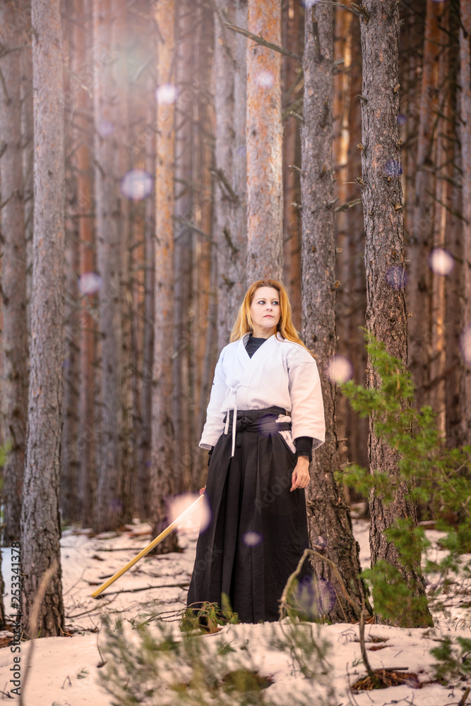 Female warrior. Woman with wooden sword practicing aikido in the snow Female warrior. Woman with wooden sword practicing aikido in the snow