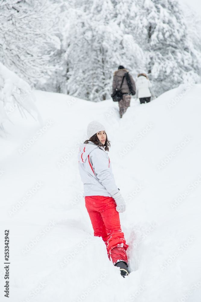 beautiful girl in a winter sports jacket looked around. girl with friends is walking on snow.