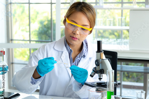 Woman Scientists researching in laboratory. Professional science focus pipetting solution into the glass cuvette.