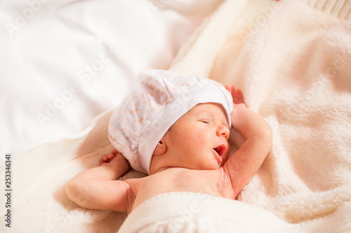 newborn is yawning, boy is lying on a white blanket. copy space for text