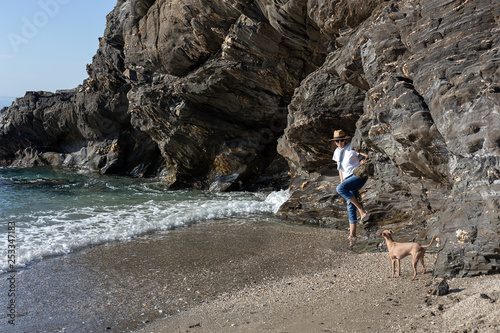 Beautiful brunette woman playing with dog on the beach