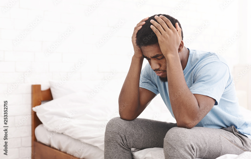Young sad man touching his head and keeping eyes closed Young sad man touching his head and keeping eyes closed