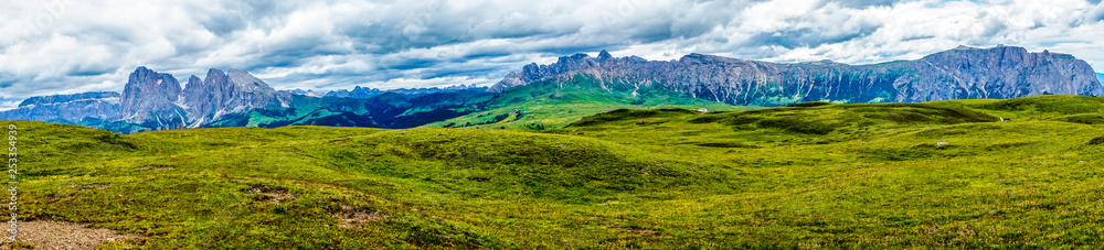 Alpe di Siusi, Seiser Alm with Sassolungo Langkofel Dolomite, a large green field with a mountain in the background panorama Alpe di Siusi, Seiser Alm with Sassolungo Langkofel Dolomite, a large green field with a mountain in the background panorama