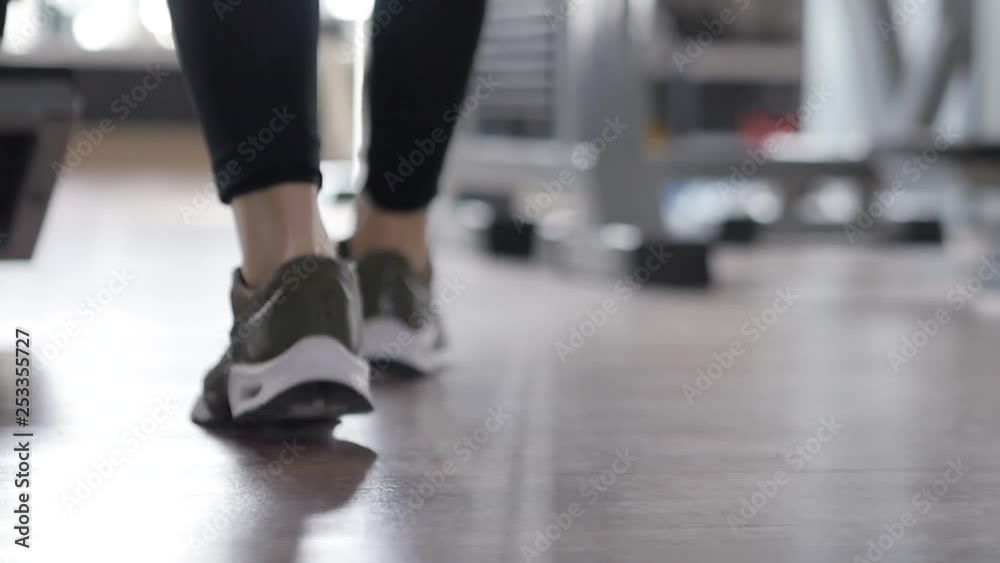 Slow motion tracking shot following a woman's feet as she walks through the gym Slow motion tracking shot following a woman's feet as she walks through the gym
