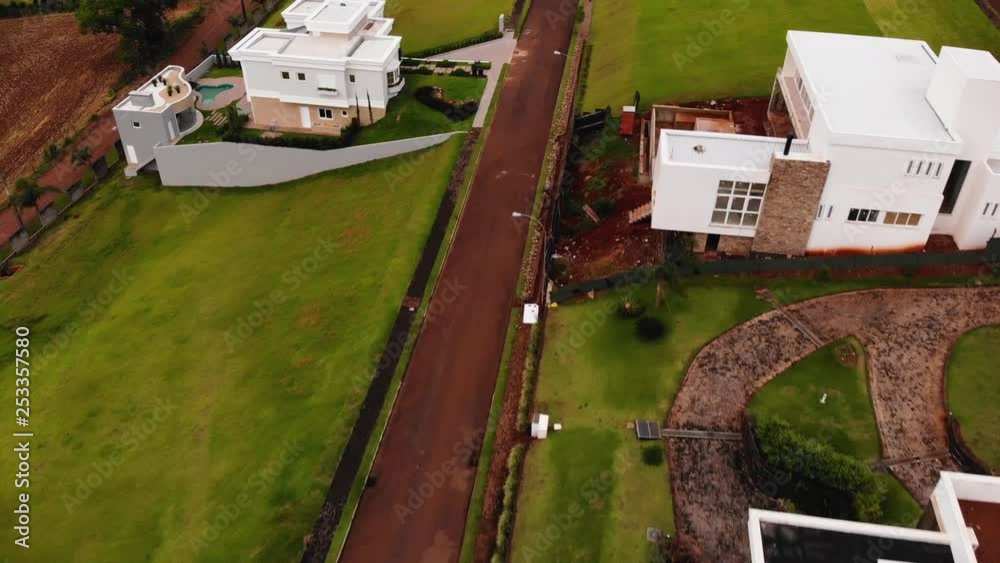 MANY DRONE FLIGHTS INSIDE A CONDOMINIUM WITH HOUSES AND LOTS OF GRASS AND TREES. SOME CITY REVEAL FLIGHTS OVER A HOUSE REVEALING THE CITY AT THE END. MANY SUNNY DAYS WITH SOME CLOUDS.