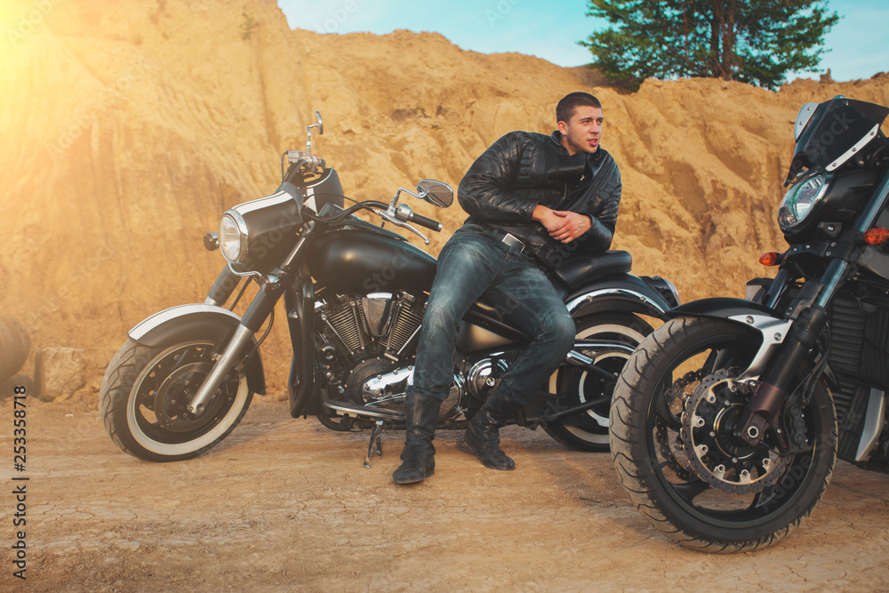 Fototapeta premium Smiling happy biker in sitting unknown on big chopper bike on road