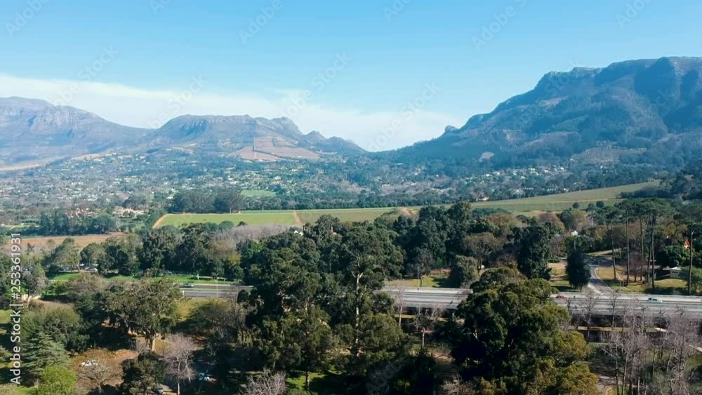 Hovering above a park in Cape Town, South Africa overlooking a vista of mountains, greenery and highways.