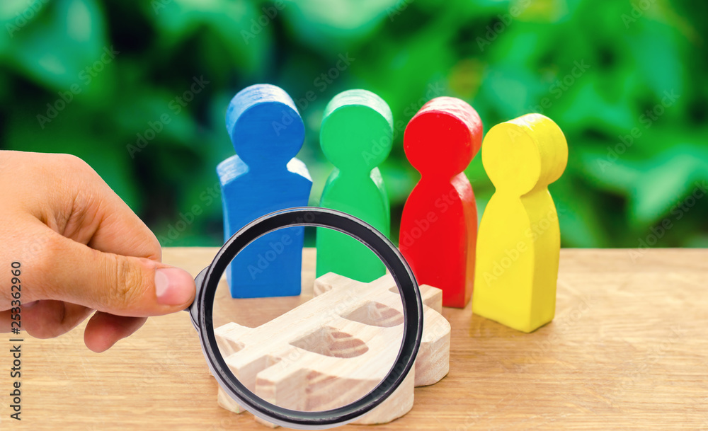 Fototapeta premium magnifying glass is looking at Four multi-colored figures of people surround a bitcoin figure. Conceptual conduct of activities around cryptocurrency and blockchain technology. Selective focus