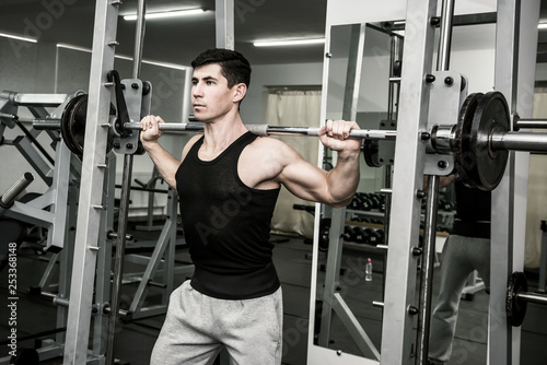 Young athletic man lifting dumbbell in gym
