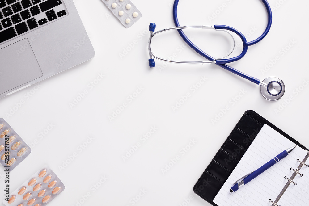 Top view of doctor desk with stethoscope, latptop, pills and blank paper on clipboard with copy space, flat lay shot. Top view of doctor desk with stethoscope, latptop, pills and blank paper on clipboard with copy space, flat lay shot.