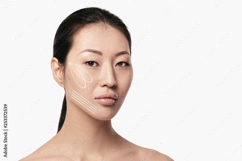 Spa portrait of attractive asian woman with arrows on her face on white background. Face lifting concept. Plastic surgery treatment, medicine Spa portrait of attractive asian woman with arrows on her face on white background. Face lifting concept. Plastic surgery treatment, medicine