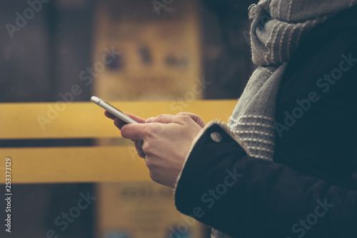 Young woman uses a smartphone. Daily life of modern people. Shallow depth of field with instagram fliter and noise. photo