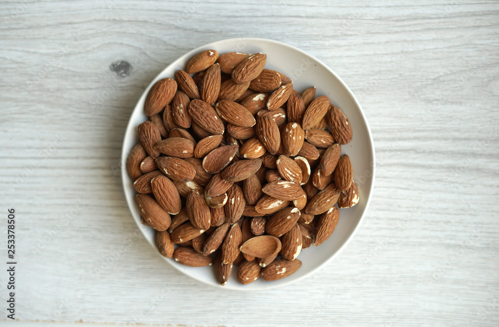 Healthy food for background image close up almond nuts. Texture on white grey table top view. Nut on the cup plate Healthy food for background image close up almond nuts. Texture on white grey table top view. Nut on the cup plate