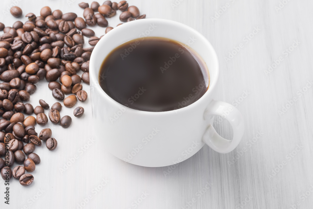 Obraz premium a cup of black natural coffee, coffee beans, on a light wooden table