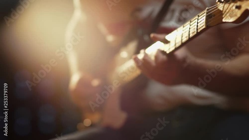 A colorful shallow depth of field close up of a Fender Telecaster finger board with beautiful lighting as it is picked over pickup and played by a male in jeans and t-shirt. photo