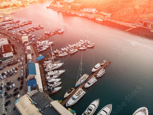 Aerial view of sunset over Balaklava, Crimea sea bay with many yachts and boats in resort coast between mountains. Beautiful tourist luxury European sunny town with harbour