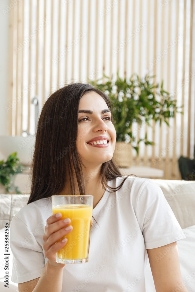 Brunette woman with closed eyes holding glass with orange juice Brunette woman with closed eyes holding glass with orange juice