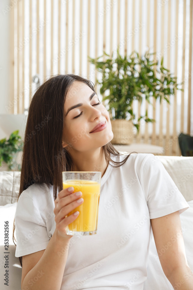 Brunette woman with closed eyes holding glass with orange juice Brunette woman with closed eyes holding glass with orange juice
