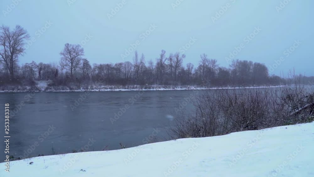 Snow falling in storm by river, Slow Motion, Pan to Left Snow falling in storm by river, Slow Motion, Pan to Left