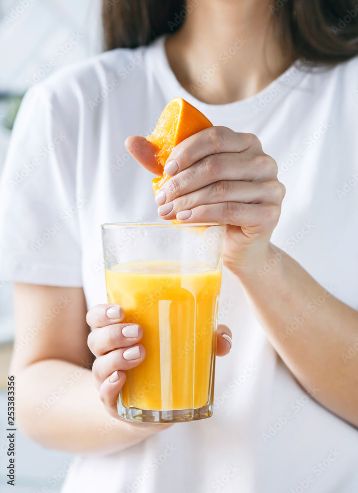 Brunette woman squeezes orange juice at the light kitchen Brunette woman squeezes orange juice at the light kitchen