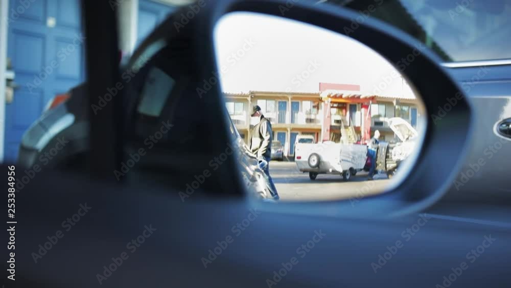 Slow motion shot through wing mirror of passing by man at car park Slow motion shot through wing mirror of passing by man at car park