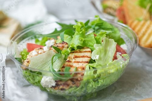 Tasty appetizing fresh salad with chicken, tomatoes, cucumbers and cheese parmesan in bowl. Close-up