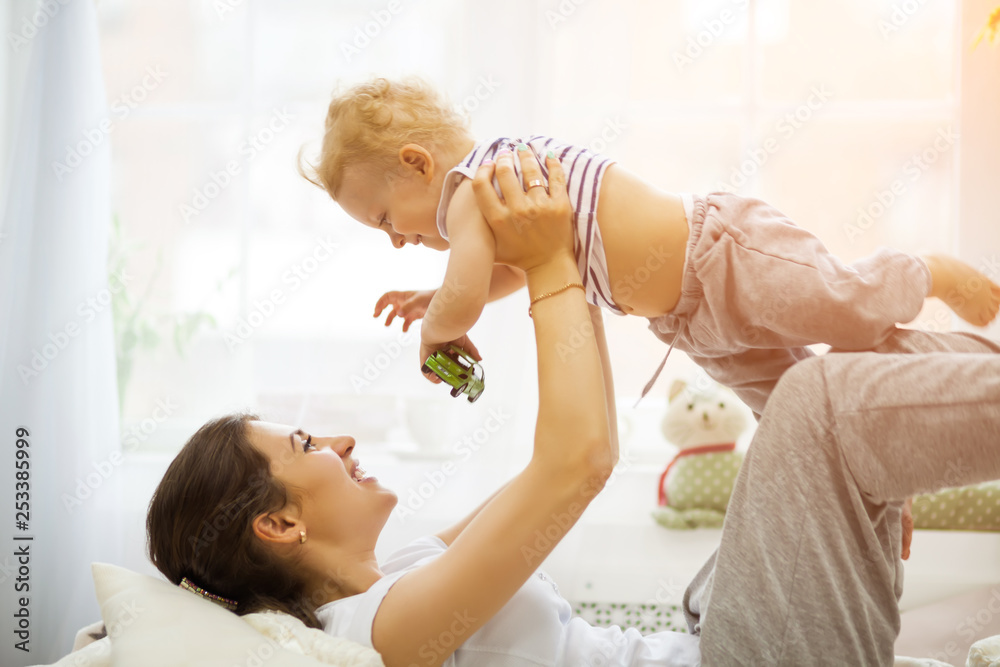 Young mother kissing her baby lying on the bed